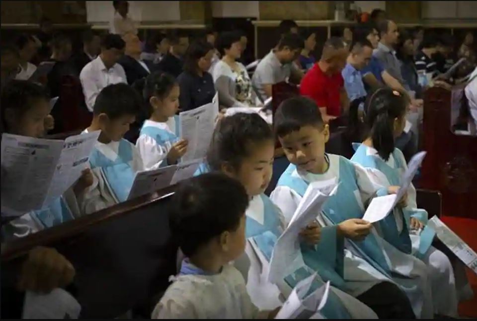 Children look at a church bulletin