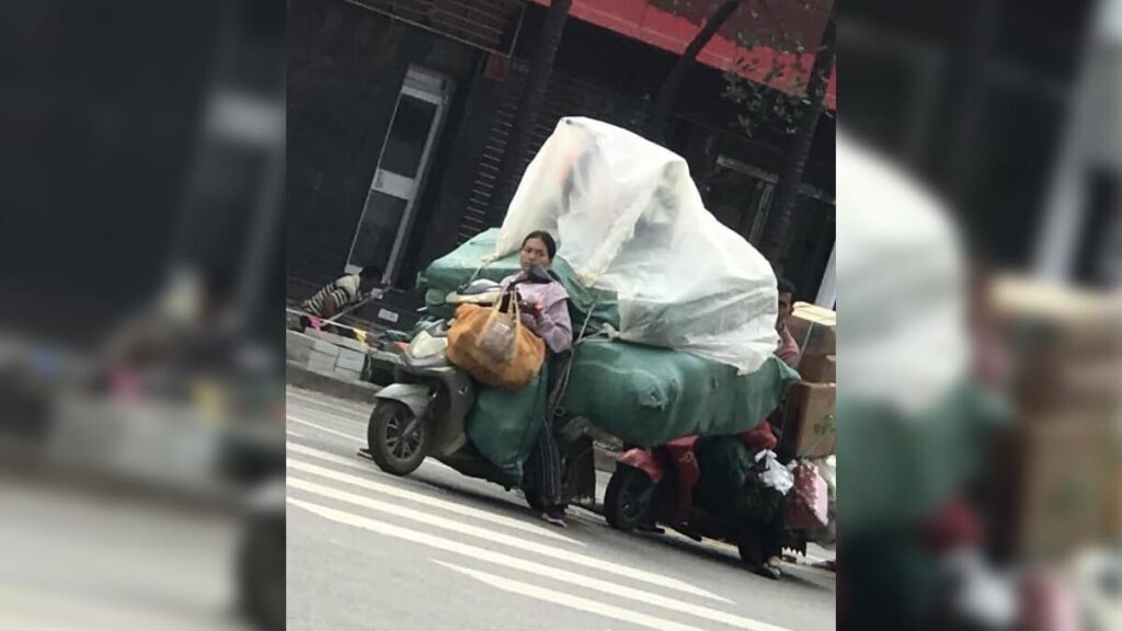 A woman on motorbike transporting good