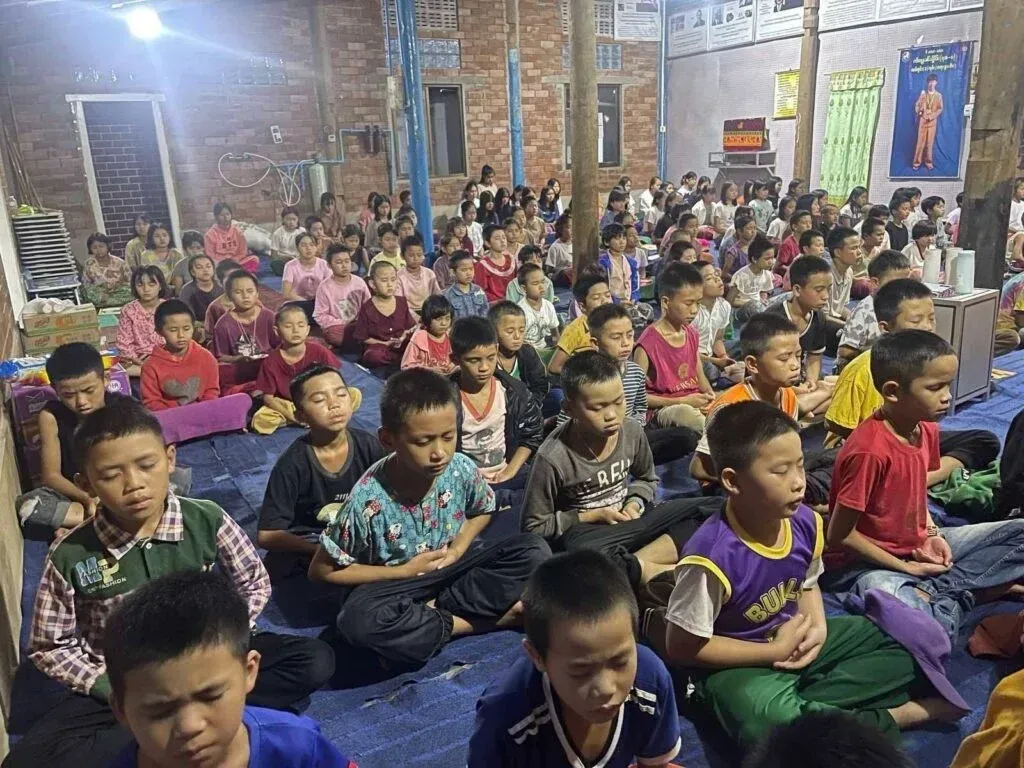 Displaced children at the school practicing meditation