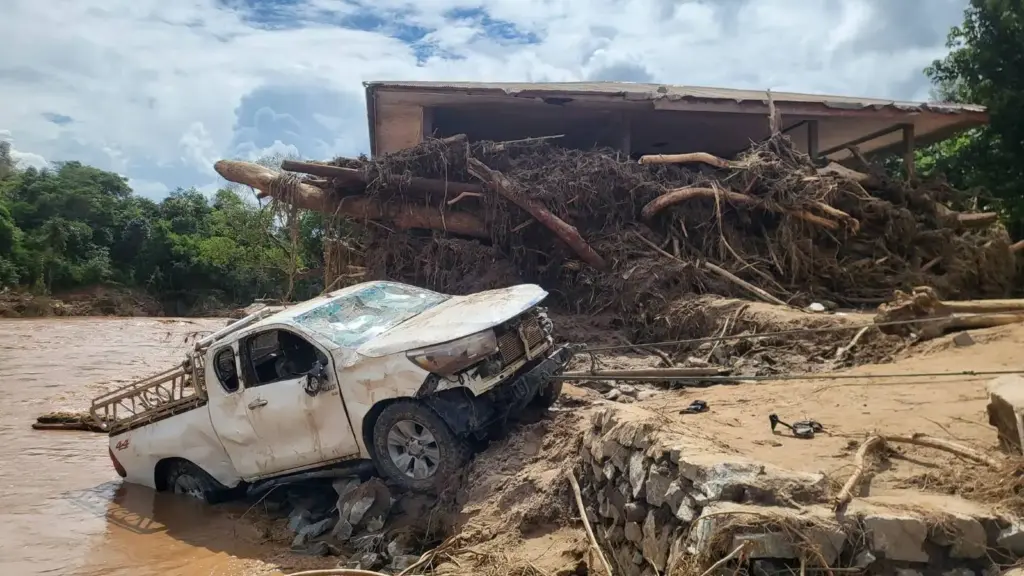 A truck and a home damaged by flooding