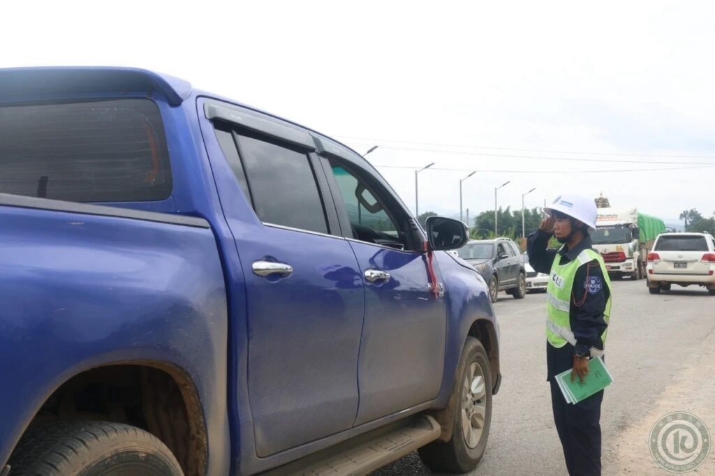 A Kokang (MNDAA) member checks a driver’s documents at a checkpoint in Northern Shan State