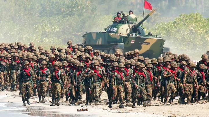 Junta troops march alongside an armored vehicle during a military exercise in Myanmar